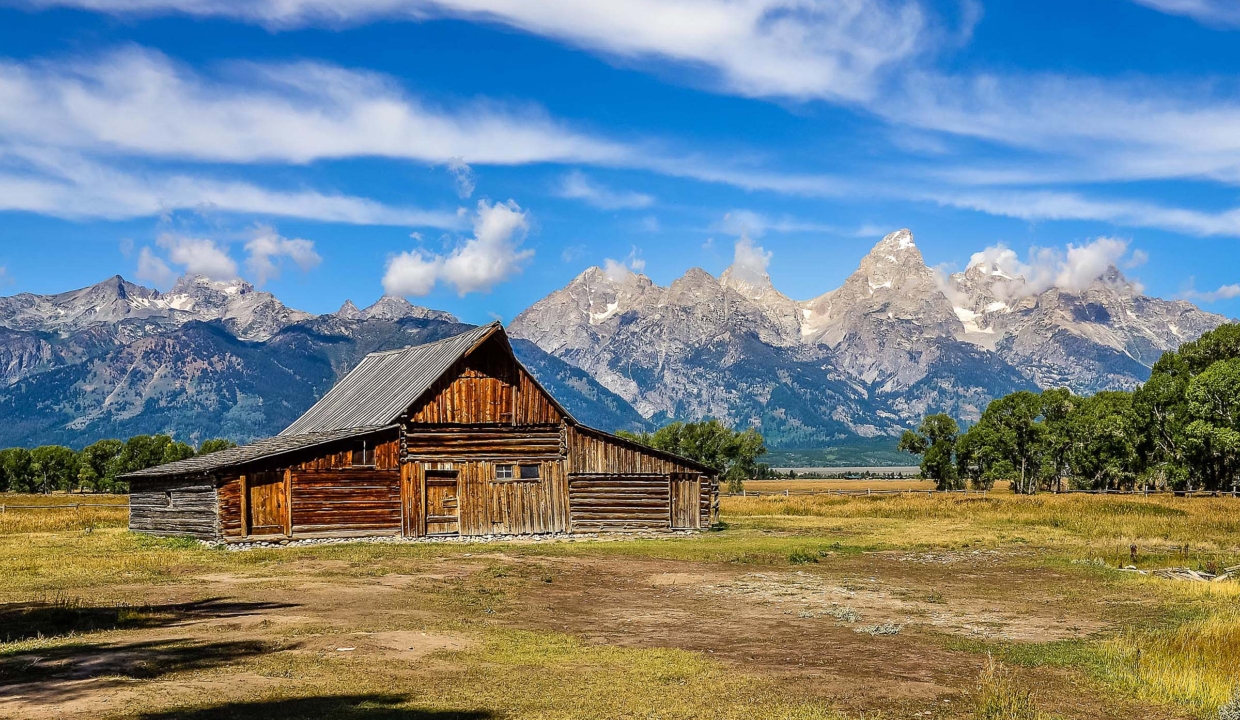 Scenic View Of Grand Teton With Old Wooden Farm